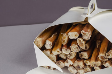 Pet treats in a in a white paper box on a gray background. Dried