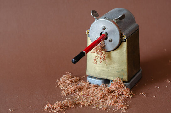 Old sharpener, pencil and shavings on brown background. Vintage