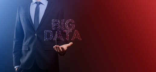 Businessman in a suit on a dark background holds the inscription BIG DATA. Storage Network Online Server Concept.Social network or business analytics representation