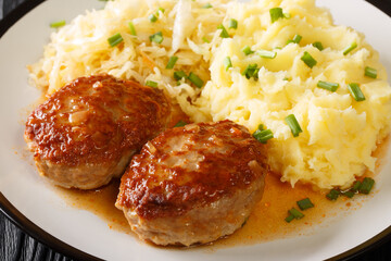 Tasty menu Norwegian pork meatballs Medisterkaker served with mashed potatoes and sauerkraut close-up in a plate on the table. horizontal