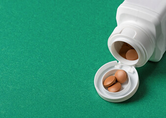 dose of pills in white open container on dark green background.Pharmaceutical concept 
