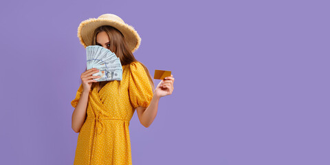 Caucasian woman 20s wearing straw hat holding credit card and fan of dollar cash isolated over purple background