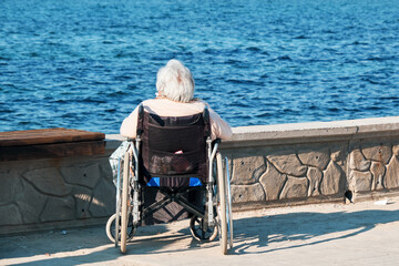Fototapeta premium Lonely elder senior woman in wheelchair watch the sea