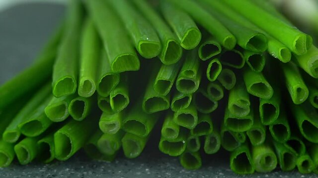 Camera movement on fresh cut green onions with water drops on black tray. Close up of greens. Macro food background