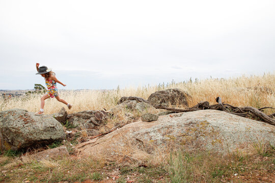 Distant shot of a young girl playing on rocky outcrop in grassy field