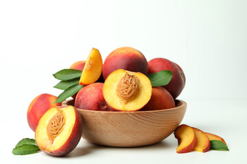 Wooden bowl with peach fruits on white table