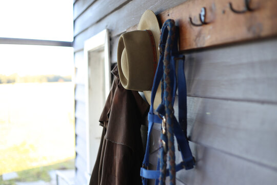 Outdoor riding gear hanging on hooks on weatherboard wall
