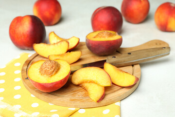 Board with peach fruits, knife and kitchen towel on white textured table