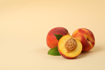 Ripe peach fruits with leaves on beige background