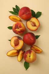 Ripe peach fruits with leaves on beige background