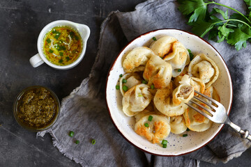 Dumplings with meat filling. Top view. Dark background. Fried dumplings. The concept of a delicious lunch or dinner. Food on a fork.