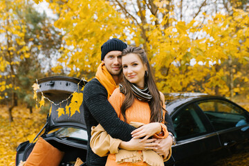 Fototapeta na wymiar A young couple in love embraces in the autumn forest, walking and enjoying nature