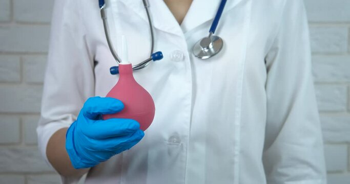 Doctor hand with enema. A professional nurse in uniform hold en enema in her hands.