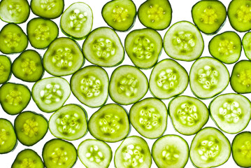 Cucumbers in section on a white background. Pieces of cucumber are illuminated by light. Texture of sliced cucumber slices.
