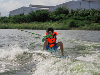 Asian boy learning wake surfing.