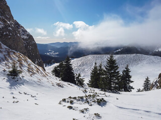 Fototapeta na wymiar Gusty wind blowing over the snowy peaks of the Ciucas mountains in Romania , part of the east European Carpathian mountains , wintertime landscape.