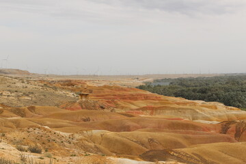 Desert landscape in Xinjiang, China, dry and colorful rocks, wind power system, the windmill at the back tells the technology development in the desert