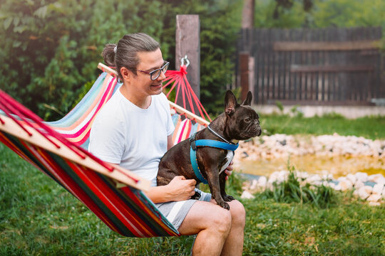 person and french bulldog relaxing in a hammock