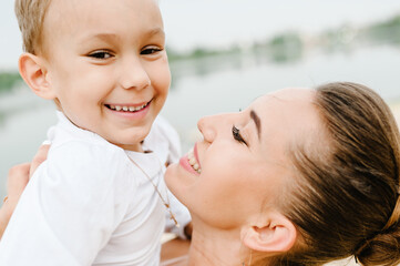 Portrait of a mother hugging son on hands on nature on summer day. Mom and boy playing in the park. Concept of happy family. Close Up.
