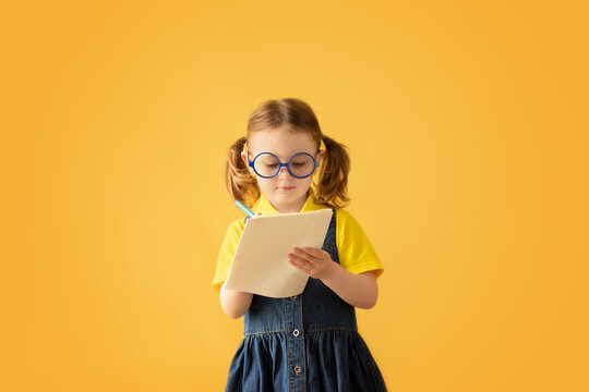 Child making notes. Kids dreams.Isolated on yellow background.Education background. Kid back to school. - Powered by Adobe
