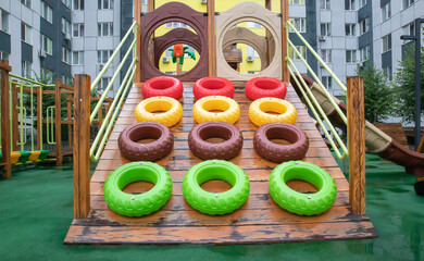 A courtyard of high-rise buildings with a modern and large playground made of wood and plastic on a rainy summer day without people. Empty outdoor playground. A place for children's games and sports.