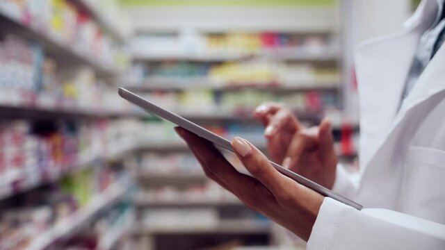 Close up female pharmacist typing on digital tablet