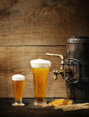Glasses of beer and an old keg with a tap on a wooden table. Craft brewing.