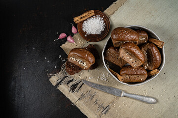 freshly baked bread on a linen tablecloth with salt and a knife on a dark kitchen table.