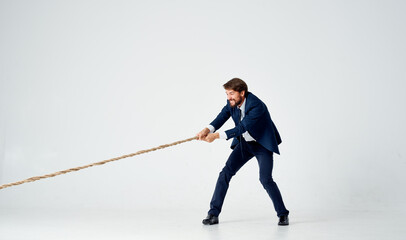 business man in a suit pulls the rope studio light background © SHOTPRIME STUDIO