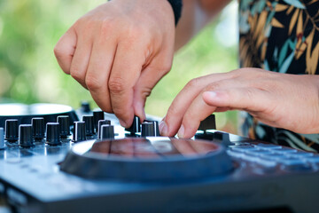 DJ Hands creating and regulating music on dj console mixer in beach club stage. 