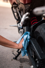 Vertical photography cleaning and drying all the elements of the motorcycle with a cloth.