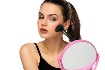 teen girl applying makeup with a makeup brush on her face