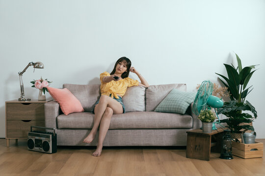 boring summer vacation korean woman finding no tv shows or programs that interest her. portrait of asian young lady propping head and whiling away time being a couch potato