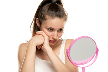 young sad woman is bored and looking at herself in the mirror