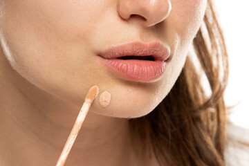 Naklejka premium a woman applies concealer to a pimple on her chin
