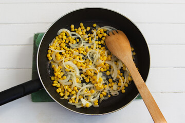 Fried corn onion hot pan white wooden background
