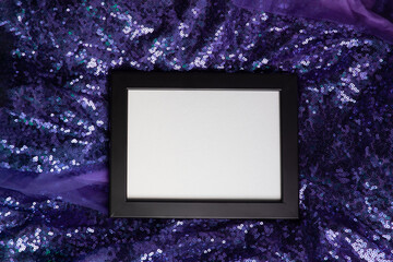 Black frame on purple sparkling fabric background