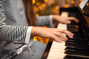 Girl's hands on the piano, close-up, beautiful bokeh in the background, woman playing the piano....
