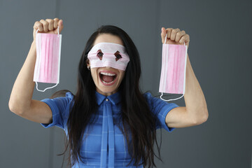 Smiling crazy woman with protective mask in front of eyes is holding mask in hands