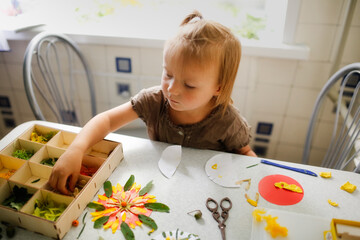 Cute kid exploring leaves and petals at home, child making crafts from natural materials, natural...