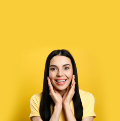 Portrait of happy young woman with beautiful black hair and charming smile on yellow background