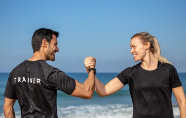 A fitness trainer and a client, a European woman, shake hands. Against the background of the sea in summer.