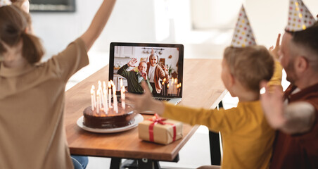 Little girl receiving congratulations from grandparents online while celebrating birthday with family at home
