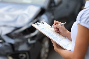 Insurance agent conducts inspection of the damaged car by filling out documents