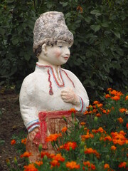 Rzeźba chłopca w kwietniku przy kwiatach