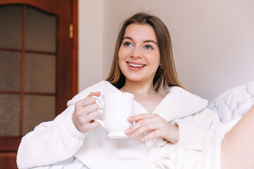 woman enjoying her tea at home sitting in bathrobe