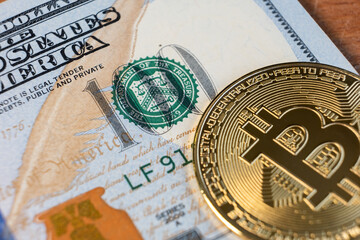 Close up of metal shiny bitcoin crypto currency coin on US dollar bills. Electronic decentralized money concept.