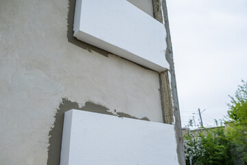 Installation of styrofoam insulation sheets on house facade wall for thermal protection.