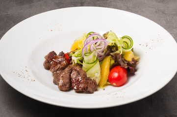 salad with veal, vegetables and orange on a white plate