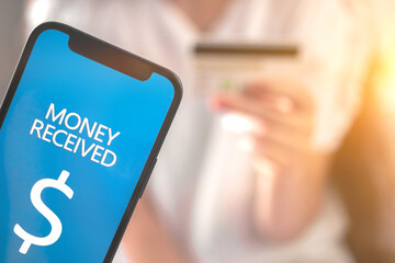 Money received screen and bank credit card in woman hand on the background